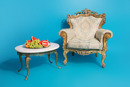 Photo of antique luxury ornament chair fruit tray table isolated on blue color background