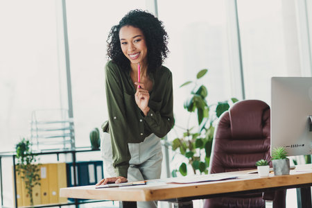 Confident Businesswoman in Modern Office Space with Natural Light and Stylish Interior During a Creative Workdayの写真素材