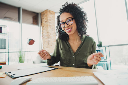 Young professional woman working confidently in her bright home office with paperwork during daylightの写真素材