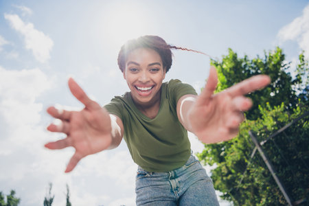 Joyful young woman reaching forward on a sunny day, embodying happiness and youthful energyの写真素材