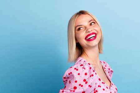 Photo of pretty lovely girl wear stylish pink print clothes look empty space isolated on blue color backgroundの写真素材