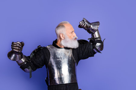 Bearded man in medieval knight armor playfully posing against a purple backdropの写真素材