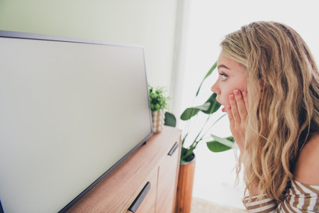 Young woman in casual striped pullover surprised in living room during daylightの写真素材