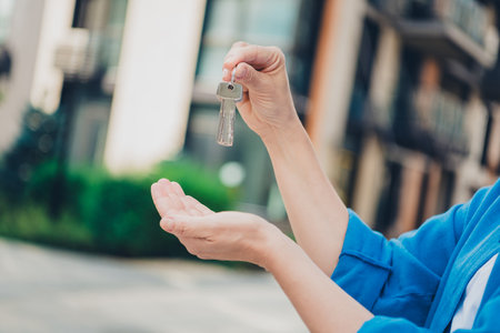 Cropped portrait of woman arm hold show new house keys wear blue shirt weekend walk city center outdoorsの写真素材