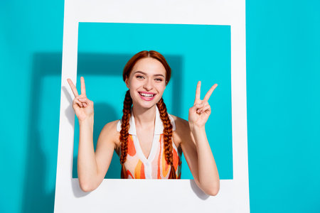 Photo of pretty young girl show v-sign paper album set card wear dress isolated on teal color backgroundの写真素材