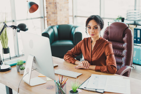 Professional young businesswoman working in a modern office setting with stylish decor and natural lightの写真素材
