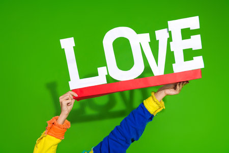 Vibrant composition showcasing the word love held stylishly against a striking green background, evoking joy and positivityの写真素材