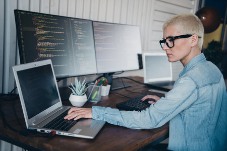A Young Professional Woman Programming on Laptop in a Modern Home Officeの写真素材