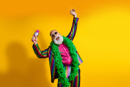 Photo of positive old showman enjoy party microphone wear striped suit boa sunglass suit isolated yellow color backgroundの写真素材