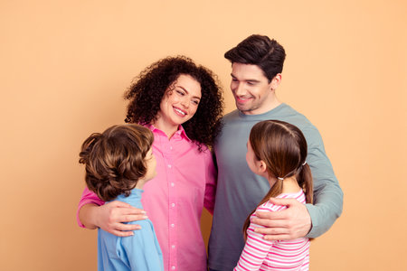 Happy family of four bonding together, parents and children share joyful moments in a cozy relaxed atmosphere with cheerful expressionsの写真素材