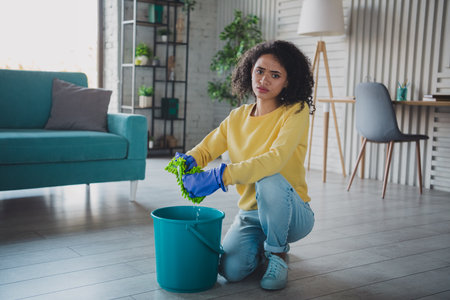 Young woman cleaning in a modern living room, wearing casual outfit and glovesの写真素材