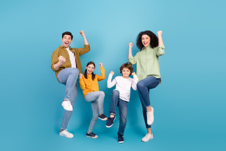 Happy family of four cheering and enjoying moments together against a vibrant blue background,...