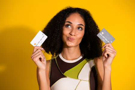 Stylish woman holding credit cards against a vibrant yellow background showcasing fun and vibrant shopping vibesの写真素材