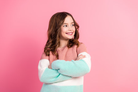 Charming cute Girl on a Pink Background in a Colorful Sweater Posing With Crossed Arms, Radiating...