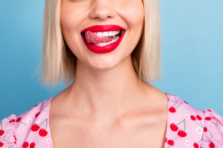 Portrait of a fashionable young woman with blonde hair and bright lipstick in a cheerful pose against a blue backgroundの写真素材