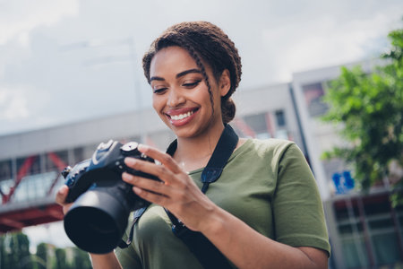 Charming young woman with camera enjoying a sunny day outdoors in urban city settingの写真素材