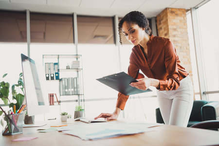 Young businesswoman analyzing documents in a bright modern office workspaceの写真素材