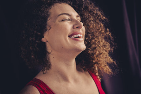 Smiling woman with curly brown hair exuding positivity in a studio setting