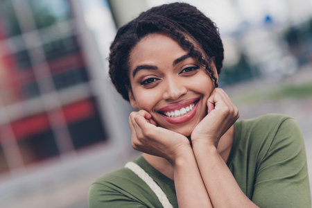 Charming young woman with afro hairstyle enjoying a casual day outdoors, smiling brightlyの写真素材