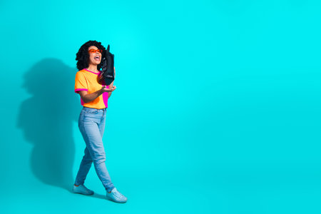 Young woman in colorful outfit posing confidently holding a retro styled phone against a vibrant...