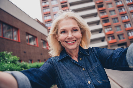 Charming senior woman in denim smiling outdoors in the city