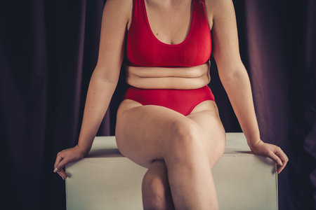 Confident young woman in red lingerie embracing natural beauty with a focus on body positivity and self loveの写真素材