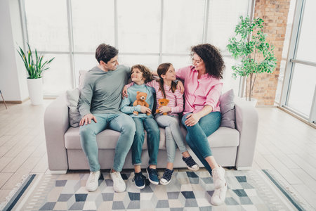 Family bonding on a casual weekend inside a modern apartment with warm daylight and cozy interior decorの写真素材