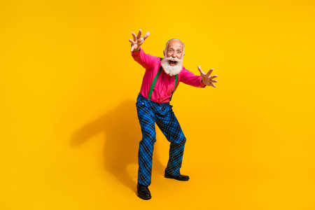 Full length photo of senior male dance stretch hands excited wear pink shirt plaid pants suspenders fancy outfit on yellow color backgroundの写真素材