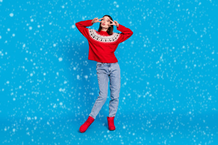 Full length body size photo woman in red sweater showing v-sign sending air kiss isolated vivid blue color backgroundの写真素材