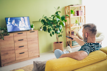 Elderly man relaxing at home watching television in cozy living room setting