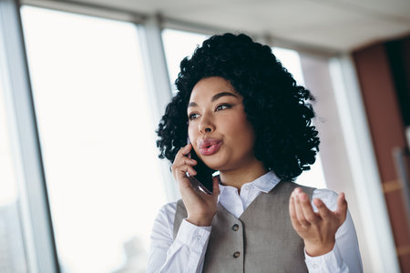 Confident businesswoman talking on the phone in a modern office, representing professionalism,...