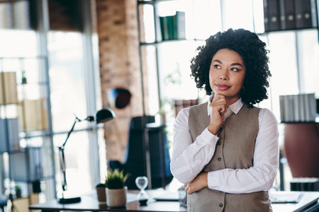 Young businesswoman in formalwear thoughtfully working in a modern office space with stylish interior and natural lightの写真素材