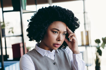 Young professional businesswoman looks concerned in office environment expressing emotions related to work challengesの写真素材