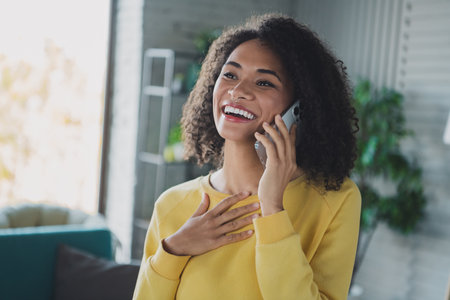 Young woman speaking on phone while smiling in home interiorの写真素材