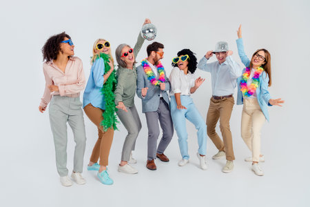 Diverse group of colleagues in vibrant costumes enjoying a celebration in an office environment with a neutral gray backgroundの写真素材