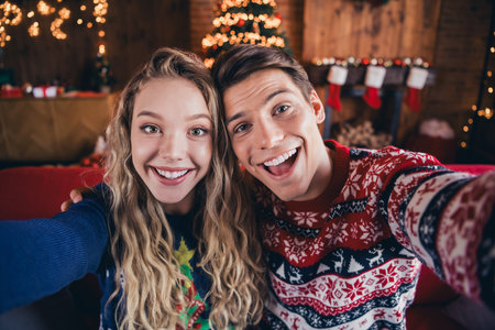 Photo of attractive excited couple wear print jumpers tacking selfie celebrating xmas indoors room home houseの写真素材