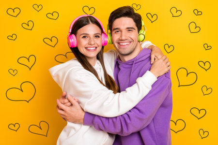Photo of two positive carefree persons hug listen mp3 playlist chill isolated on yellow color backgroundの写真素材