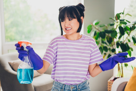 Photo of unsure uncertain lady wear violet striped t-shirt dislike cleaning indoors room home houseの写真素材