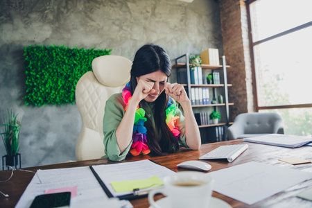 Young businesswoman in colorful outfit feeling emotional in modern office settingの写真素材