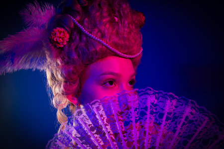 Photo of charming dreamy marie antoinette wear rich outfit hand fan cover mouth empty space isolated blue color backgroundの写真素材