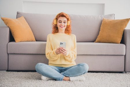 Photo of adorable sweet lady wear yellow sweatshirt headphones chatting modern device indoors room home houseの写真素材