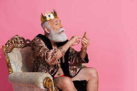 Photo of confident eccentric king character wear trendy leopard bathrobe hold push button phone isolated on pink color backgroundの写真素材