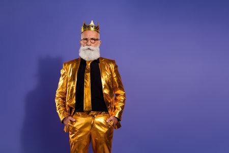 Portrait of funny eccentric aged man posing empty space wear golden shiny suit isolated on purple color backgroundの写真素材