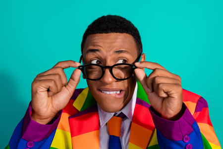 Charismatic Young Man in a Rainbow Suit Expressing Personality Against a Vibrant Turquoise...