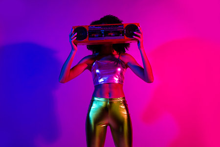 Stylish young woman in neon lights holding a retro boombox, vibrant fashion with glowing colors and...