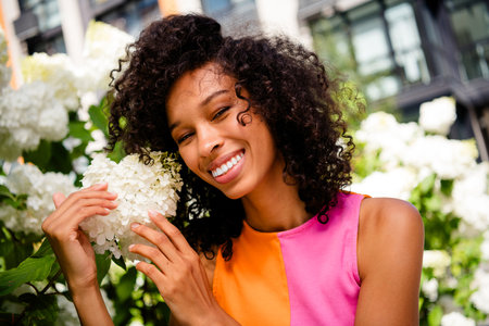 Photo of attractive young cheerful lady posing touch flowers wear colorful garment spend time enjoy...