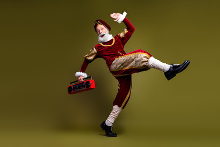 Elderly man dressed as a nobleman posing with a retro red boombox against khaki background, blending historical fashionの写真素材
