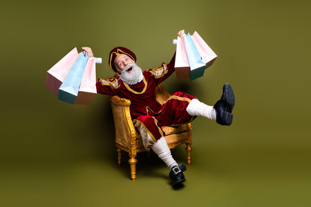 Elderly nobleman in vintage costume enjoying shopping spree on a classic antique chair against a khaki backgroundの写真素材