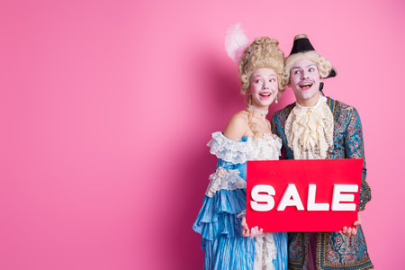 Elegant couple in vintage costumes enjoying a fun theme party against pink background
