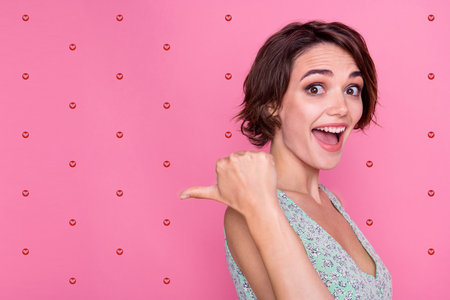 Photo side cadre of young lady open mouth impressed emotion surprised indicate finger empty space novelty isolated on pink color backgroundの写真素材